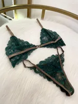 Conjunto de lencería compuesto por un bralette de encaje verde esmeralda con cierre frontal y una tanga a juego con tiras regulables, ambos con detalles de ribetes en color marrón.