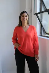 Sweater de punto color naranja, con cuello en V, manga larga y diseño holgado con tajos laterales en el ruedo.