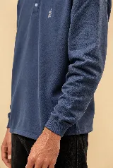 Buzo de manga larga estilo rugby color azul petróleo, con cuello beige en contraste, tapeta con botones y pequeño bordado en el pecho. Confeccionado en algodón pesado con fit relajado.