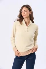 Buzo tejido combinado de color beige, con cuello alto, medio cierre metálico y puños y ruedo acanalados en tono tostado.