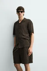 Bermuda de corte regular confeccionada en tejido fluido con textura jacquard geométrica. Presenta cintura elástica con cordón ajustable, bolsillos laterales y bolsillos traseros de vivo.