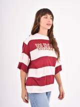 Remera de corte holgado con diseño de rayas horizontales anchas en tonos azul y blanco, cuello redondo y mangas cortas.