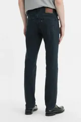 Jean de corte slim fit con tiro medio, confeccionado en denim de color negro con acabado desgastado.