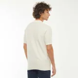 Remera polo de manga corta color crema, de punto con textura en zigzag y cuello clásico con tres botones.