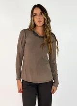 Remera de manga larga color marrón, con cuello redondo adornado con un detalle de textura desflecada en el borde.