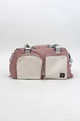Bolso deportivo color rosa con detalles en beige y gris. Tiene doble asa de mano y correa de hombro ajustable. Cuenta con dos bolsillos frontales con cierre y logo de la marca en la esquina inferior derecha.