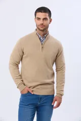Buzo tejido de punto en color beige, con cuello alto y cierre frontal parcial. Presenta puños y ruedo acanalados, con un detalle de cuero en el tirador del cierre.
