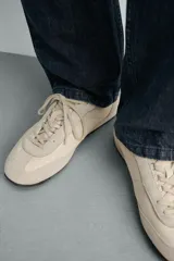 Zapatilla de cordones fabricada en piel con acabado serraje y combinación de piezas de tejido, con suela dentada en contraste de color y pespuntes decorativos.