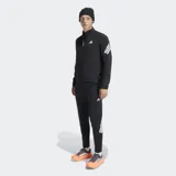 Campera deportiva Adidas de corte clásico, color negro con detalles en blanco. Presenta cierre frontal, cuello alto, bolsillos con cremallera y las icónicas tres bandas de la marca en las mangas. Incluye inserciones de malla para mayor ventilación y dobladillo con cordón elástico ajustable.