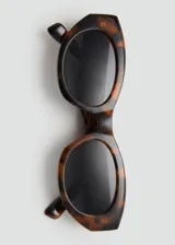 Gafas de sol con montura ovalada de pasta con estampado carey y lentes oscuras.