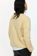 Saco de punto suave con lana, de corte holgado con hombros caídos, cuello redondo y cierre frontal con botones. Presenta terminaciones acanaladas en cuello, puños y ruedo.