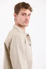 Sobrecamisa gris oscuro de manga larga, con cuello clásico, cierre frontal con botones y dos bolsillos de parche en el pecho.