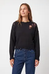 Buzo de punto negro con diseño efecto desgastado, cuello redondo, mangas largas y detalles rotos en los hombros, el cuello y el ruedo.