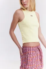 Top musculosa blanco de canalé con cuello redondo, corte ajustado y detalle de botones a presión en el lateral.
