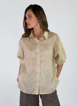 Camisa de lino color beige, de corte holgado, con cuello camisero, cierre frontal con botones y mangas cortas abullonadas.