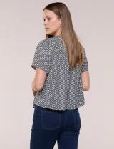 Blusa de manga corta con micro-estampado geométrico en blanco y negro, escote redondo con abertura tipo gota y lazo fino para atar.