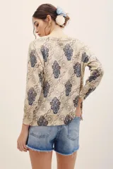Sweater de punto color beige con estampado geométrico y floral en tonos azules y burdeos, de manga larga y cuello redondo.