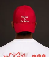 Gorra roja de sarga con visera curva, hebilla ajustable en la parte trasera y bordado frontal con la frase "Nosotros Dos y Un Boteco".