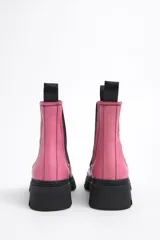 Botín Chelsea de cuero color rosa con puntera y suela track color negro. Cuenta con elásticos laterales negros y tiradores en la parte trasera.