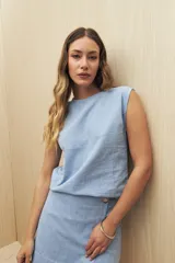 Top sin mangas de lino y viscosa, color negro, con escote redondo y caída relajada. Presenta hombros levemente marcados y botones forrados en la espalda.