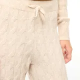 Pantalón de punto con diseño de trenzas, color beige, de corte recto y holgado. Cuenta con cintura elástica con cordón ajustable.