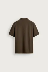 Remera polo regular fit de color gris oscuro, confeccionada en tejido de algodón con textura de rayas verticales. Cuenta con cuello solapa, cierre frontal con botones y mangas cortas con terminación en rib.