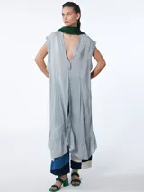 Túnica maxi celeste a rayas verticales blancas, sin mangas, con escote en V profundo en la espalda y volados en el ruedo.