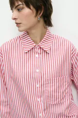 Camisa de manga larga a rayas verticales rojas y blancas, con cuello clásico, cierre frontal con botones y bolsillo de parche en el pecho.