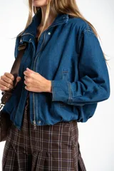 Campera bomber de jean azul con cierre frontal metálico, cuello alto y diseño oversize. Presenta costuras reforzadas y puños rectos.