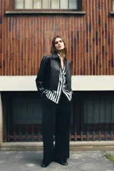 Pantalón de tiro alto color bordó, con pinzas delanteras, bolsillos frontales y falsos bolsillos con solapa en la espalda. Tiene pernera ancha y cierre frontal con cremallera, botón interior y gancho.