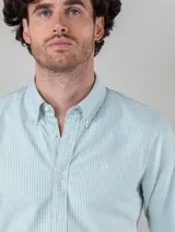 Camisa celeste de corte clásico, con cuello abotonado, manga larga y logo bordado en el pecho.