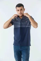 Remera cuello polo de manga corta con diseño de bloques de color, presentando una sección superior con rayas horizontales y una sección inferior lisa. Cuenta con cierre de botones en el cuello y logo estampado en el pecho.