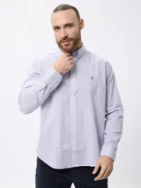 Camisa de manga larga con estampado de microcuadros en tonos azul y blanco. Presenta cuello clásico con botones, cierre frontal abotonado y detalle de logo bordado en el pecho.