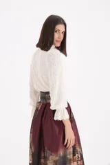 Sweater de punto calado en color crudo, con cuello alto tipo polera y mangas largas con puños con volados.