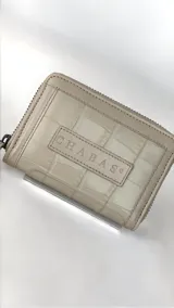 Mini billetera de cuero con textura efecto cocodrilo y cierre perimetral. Presenta un parche central con el logo de la marca grabado.