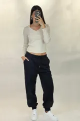 Pantalon deportivo tipo babucha de color beige, con cintura elástica ajustable mediante cordón y puños elásticos en los tobillos.