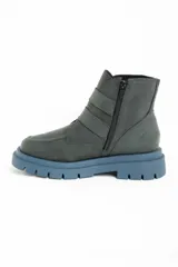 Bota corta de cuero color verde oscuro, con suela track gruesa de color celeste. Presenta dos correas ajustables con hebillas metálicas plateadas y un pequeño dije de estrella dorada en el lateral. Tiene cierre de cremallera en el interior.