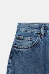 Pantalón de jean estilo baggy balloon de tiro medio, con diseño de cinco bolsillos y costuras laterales torcidas. Cuenta con cierre frontal de cremallera y botón metálico.