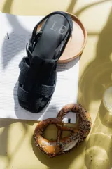 Sandalias de cuero marrón con diseño de tiras entretejidas y hebilla lateral.