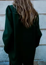 Camisa de popelín de algodón de corte oversize, color verde oscuro, con manga larga, cuello camisero y cierre frontal de botones.