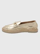 Alpargatas tipo slip-on en cuero metalizado color dorado, con detalle de herraje metálico en el empeine y suela con borde de yute trenzado.
