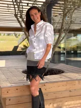 Minifalda tejida en lurex plateado y negro, con diseño a rayas horizontales y flecos con tachas en el ruedo.