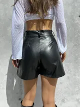 Short de tiro alto confeccionado en ecocuero elastizado, con bolsillos frontales amplios con cierre metálico.