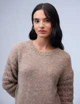 Buzo color beige de lana con mangas caladas, cuello redondo y corte holgado.