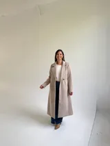 Tapado largo de paño en color beige, con solapas anchas, cierre frontal de un botón y diseño estructurado.
