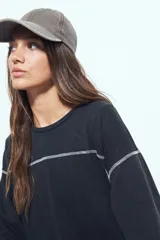 Remera de manga corta color marrón con efecto desgastado, corte oversize y costuras a la vista en color blanco. Presenta cuello redondo con cuello polo blanco superpuesto y mangas largas a rayas horizontales marrones y blancas por debajo.