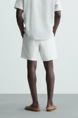 Bermuda azul marino de corte regular fit, confeccionada en tejido de algodón y lino. Cuenta con bolsillos frontales y traseros, cierre frontal con cremallera y botón.