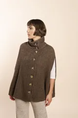 Capa color beige con textura de espiga, cuello alto con botones y aberturas laterales para los brazos. Confeccionada en lana fina sin teñir.