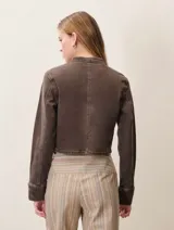 Chaqueta estilo militar de denim color marrón, con cuello redondo, cierre frontal y detalle de botones decorativos en el frente y en los puños.