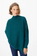 Sweater de punto color verde azulado, con cuello alto acanalado, mangas largas con hombros caídos y diseño holgado. Presenta un patrón de costuras verticales que forman un diseño de espiga en el frente.